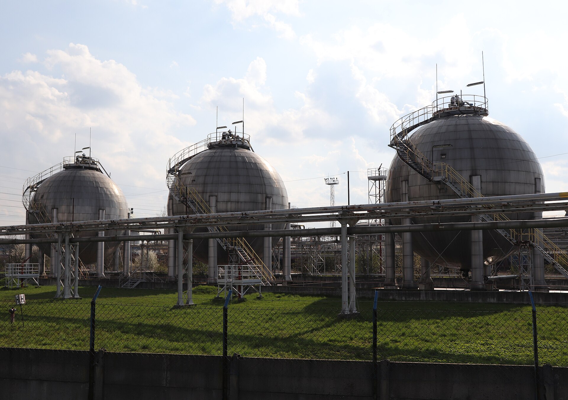 Three LPG storage spheres on concrete support legs at a gas depot